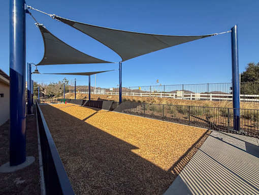 A train track with a blue pole and a white shade structure.