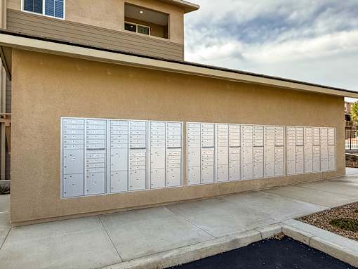 A wall of mailboxes in front of a tan building.