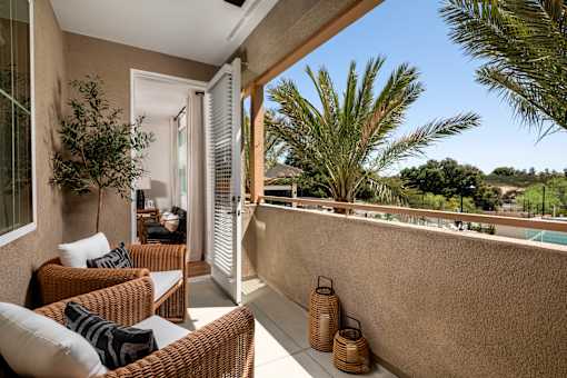 A patio with a couch, chairs, and a table with a plant on it.