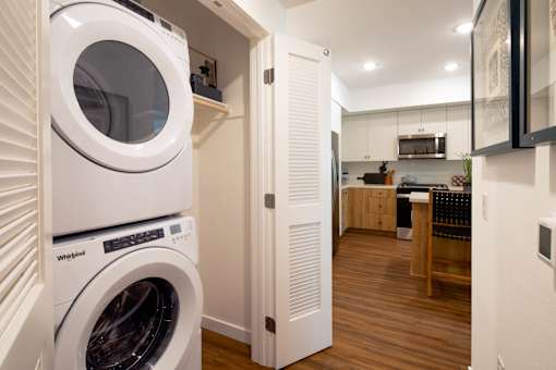 A white Whirlpool washing machine is in a small laundry room.