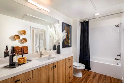 A bathroom with a white countertop and wooden cabinets.