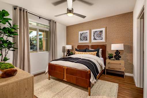 A bedroom with a bed, nightstand, and a ceiling fan.