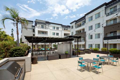 A patio with a table and chairs is surrounded by apartment buildings.