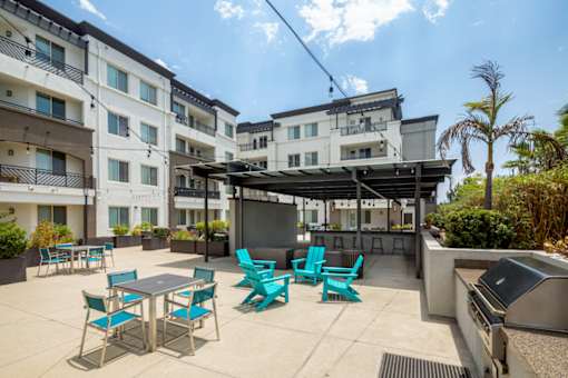 A patio with a table and chairs is surrounded by apartment buildings.
