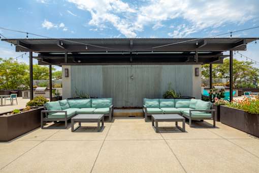 A patio area with a metal building and two green couches.