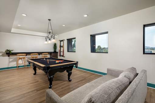 A pool table is in the middle of a room with a couch and a chair.