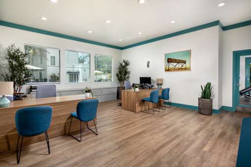 A room with blue chairs and a wooden desk.
