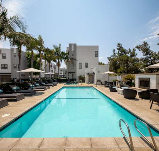 A swimming pool surrounded by lounge chairs and umbrellas.