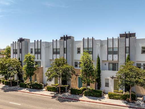 A row of modern townhouses with trees in front.