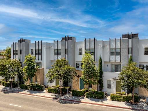 A row of modern townhouses with trees in front.