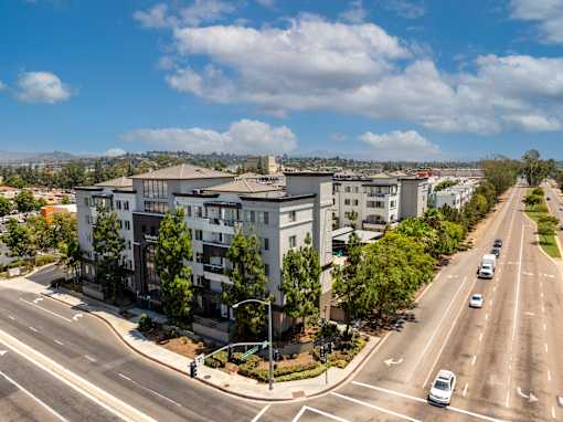 A road with cars and apartment buildings on the side.