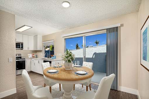 A dining room with a table set for two and a view of the backyard.