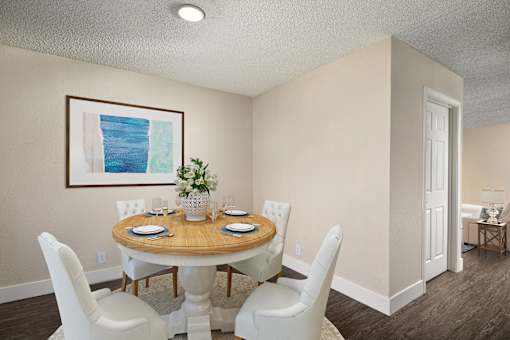 A dining room with a round table and white chairs.