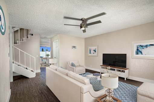 A living room with a white couch and a ceiling fan.