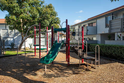 A playground with a green slide and red and green equipment.