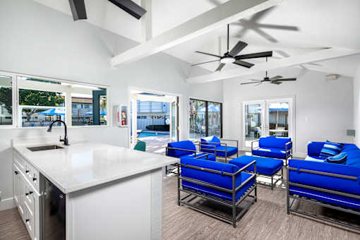 A modern kitchen with a white countertop and blue chairs.