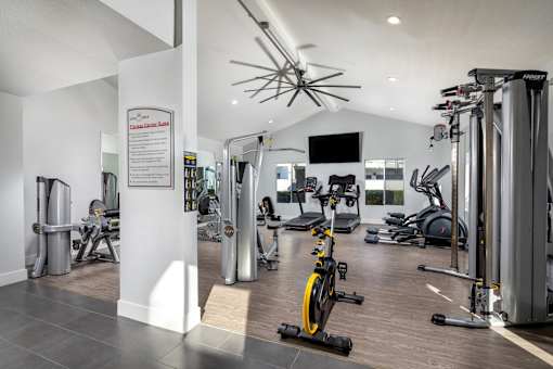 A gym with a variety of equipment including treadmills, weights, and exercise bikes.