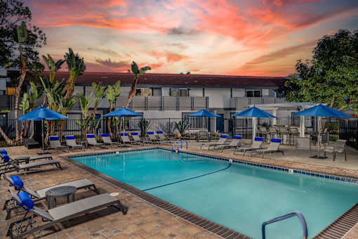 A pool surrounded by lounge chairs and umbrellas.