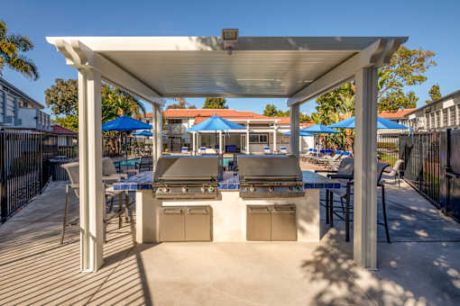 A patio with a grill and chairs under a white canopy.
