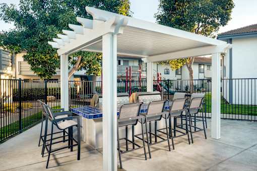 A patio with a table and chairs under a white pergola.