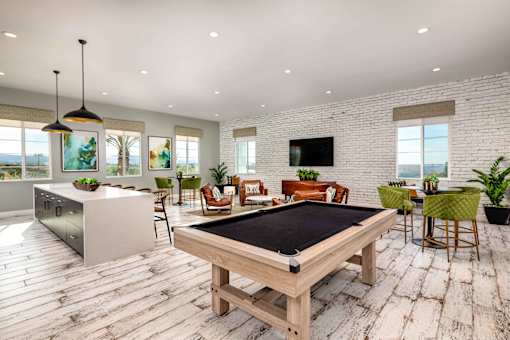 A pool table is in the middle of a room with a bar and a television at San Carlo Townhomes Apartments, Highland
