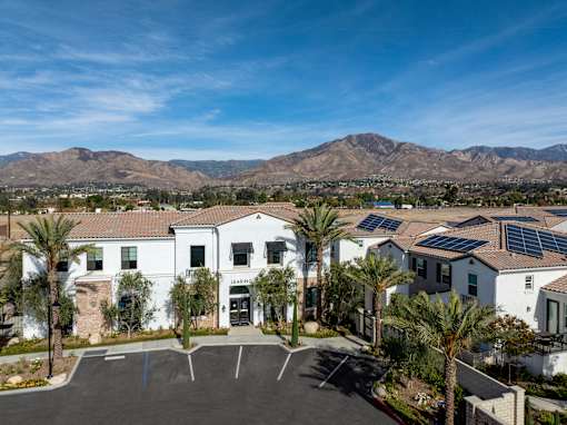 A sunny day at a housing development with a mountain in the background at San Carlo Townhomes Apartments, Highland, California