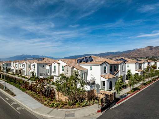 A row of houses with a mountain in the background at San Carlo Townhomes Apartments, Highland, California