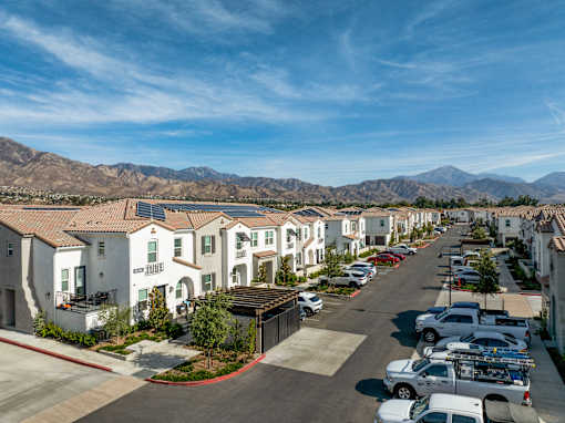 A row of houses with a mountain range in the background at San Carlo Townhomes Apartments, California, 92346