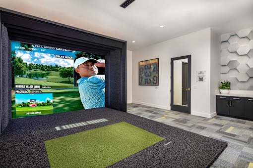 A room with a golf simulator screen and a green mat on the floor at San Carlo Townhomes Apartments, Highland, 92346