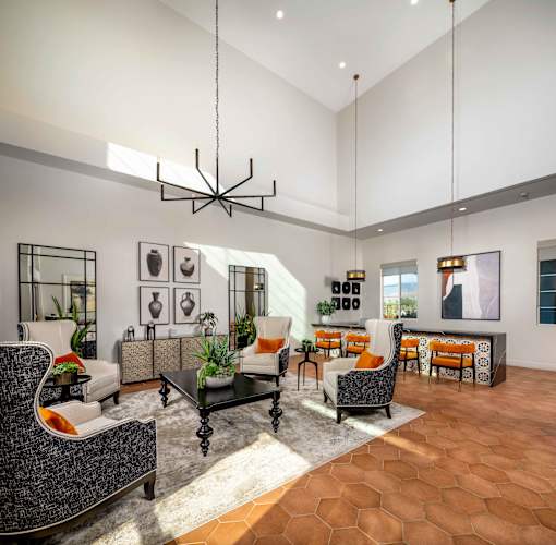 A modern living room with a black chandelier and orange accent chairs at San Carlo Townhomes Apartments, Highland