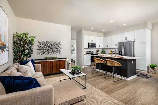 A modern living room with a beige couch and a coffee table at San Carlo Townhomes Apartments, Highland, CA