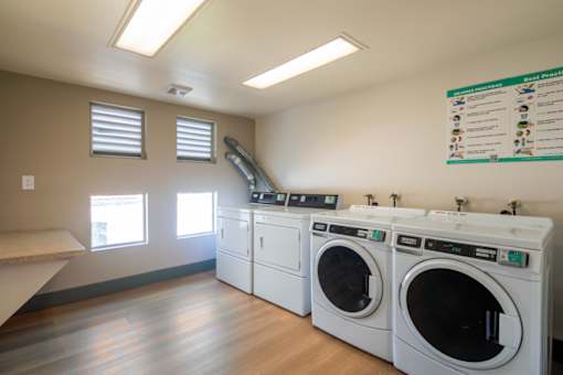 A laundromat with a sign on the wall and a row of washers and dryers.
