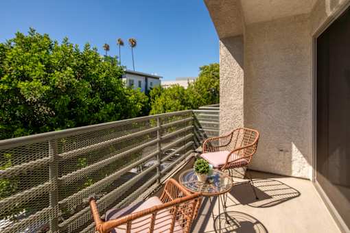 A balcony with a table and chairs overlooking a street.