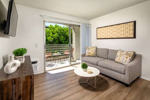 A living room with a grey couch, a white coffee table, and a wooden cabinet.