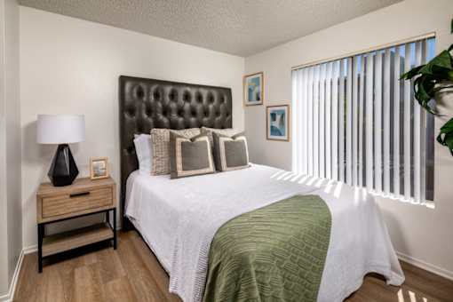 A bedroom with a large bed and a nightstand with a lamp.