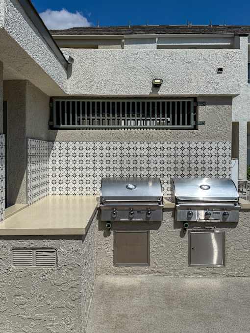 Two grills are installed on the wall of a house.