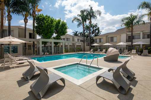 A pool surrounded by palm trees and a building.