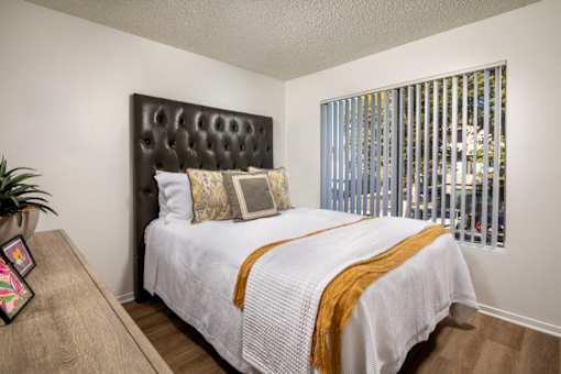 A bedroom with a white bed and a brown headboard.