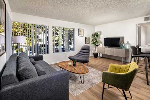 A living room with a grey couch, a green chair, and a wooden coffee table.