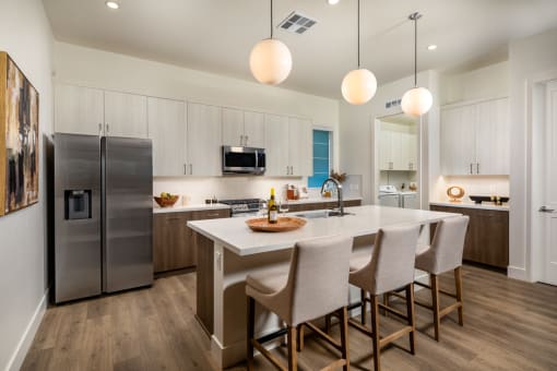 a kitchen with a large island and a stainless steel refrigerator