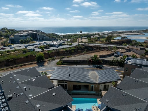 an aerial view of a house with a pool and the ocean in the background