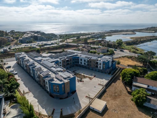 an aerial view of an apartment complex with the ocean in the background