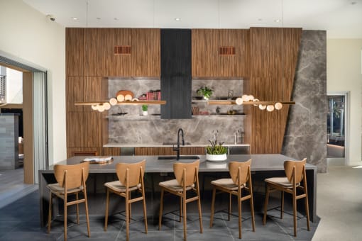 a kitchen with wooden cabinets and a long island with chairs and a sink