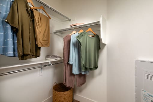 a walk in closet with clothes hanging on the wall