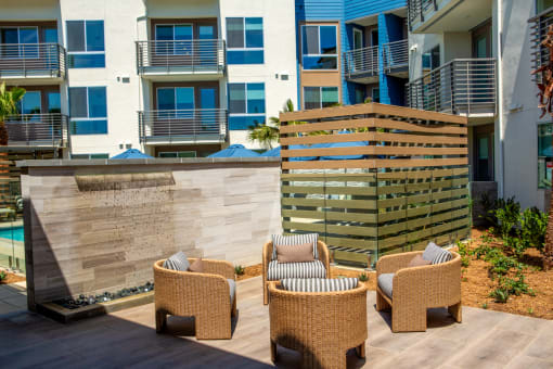 a patio with chairs in front of an apartment building