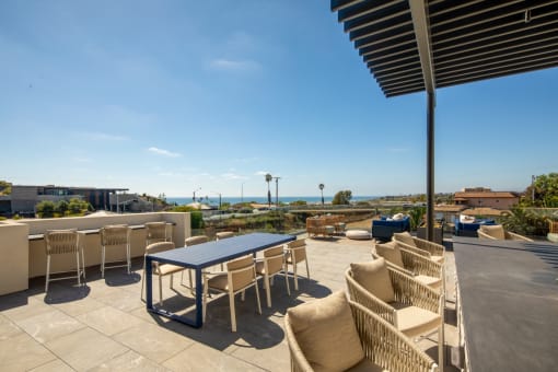 a patio with tables and chairs and a view of the ocean