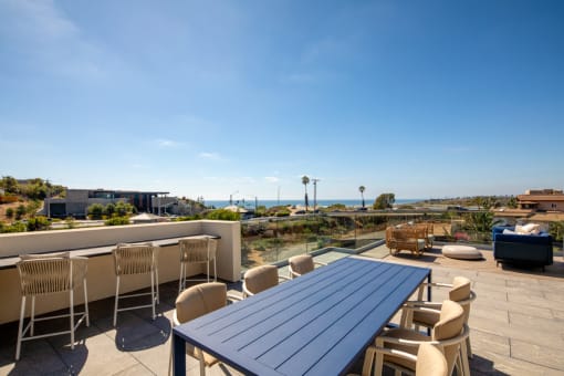 a rooftop patio with a blue table and chairs and a view of the ocean