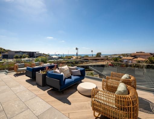 a roof deck with couches and chairs overlooking the ocean