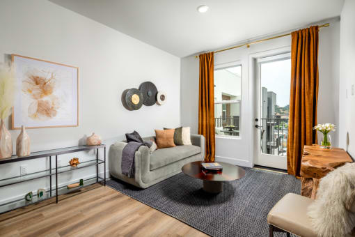 a living room with white walls and a sliding glass door that leads to a balcony at VORA LUX, San Diego California
