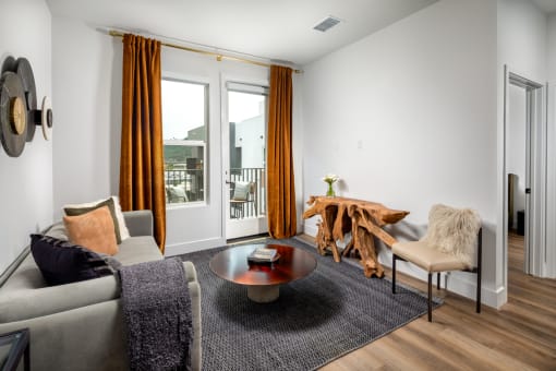 a living room with white walls and a sliding glass door that leads to a balcony at VORA LUX, California